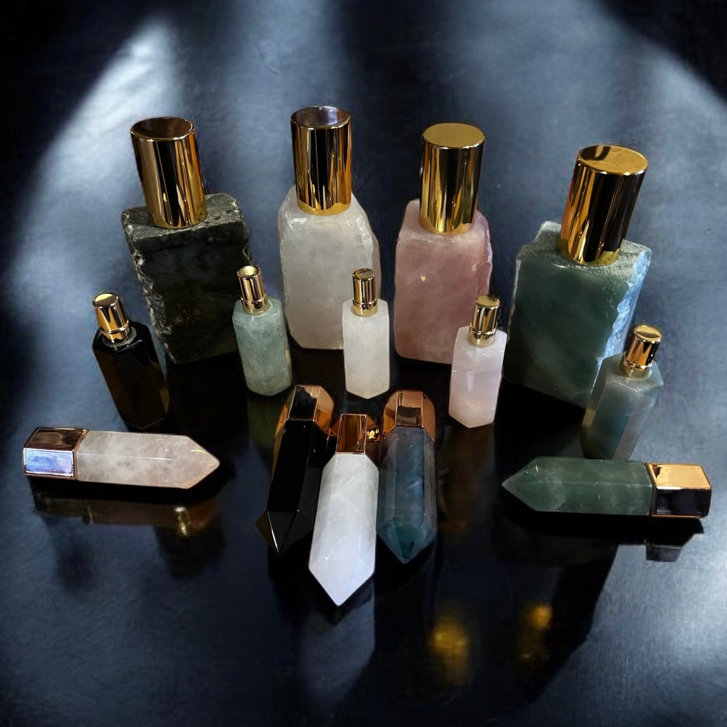 Array of various crystal perfume bottles with artistic designs in an assortment of colors and shapes, featuring gold accents and displayed together.