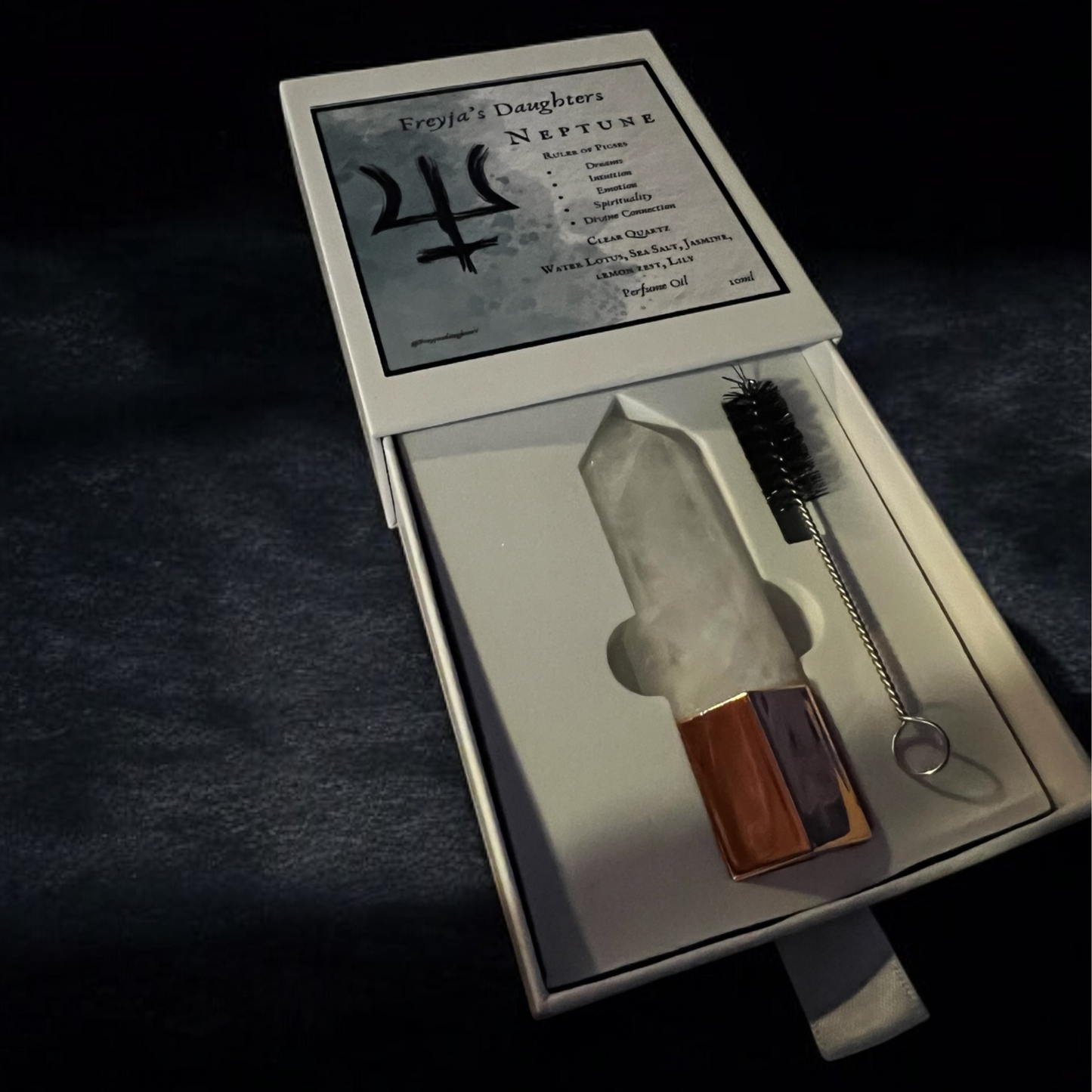Open box of Freyja's Daughters Neptune perfume featuring a clear quartz roller wand and accompanying brush, highlighting the product details.