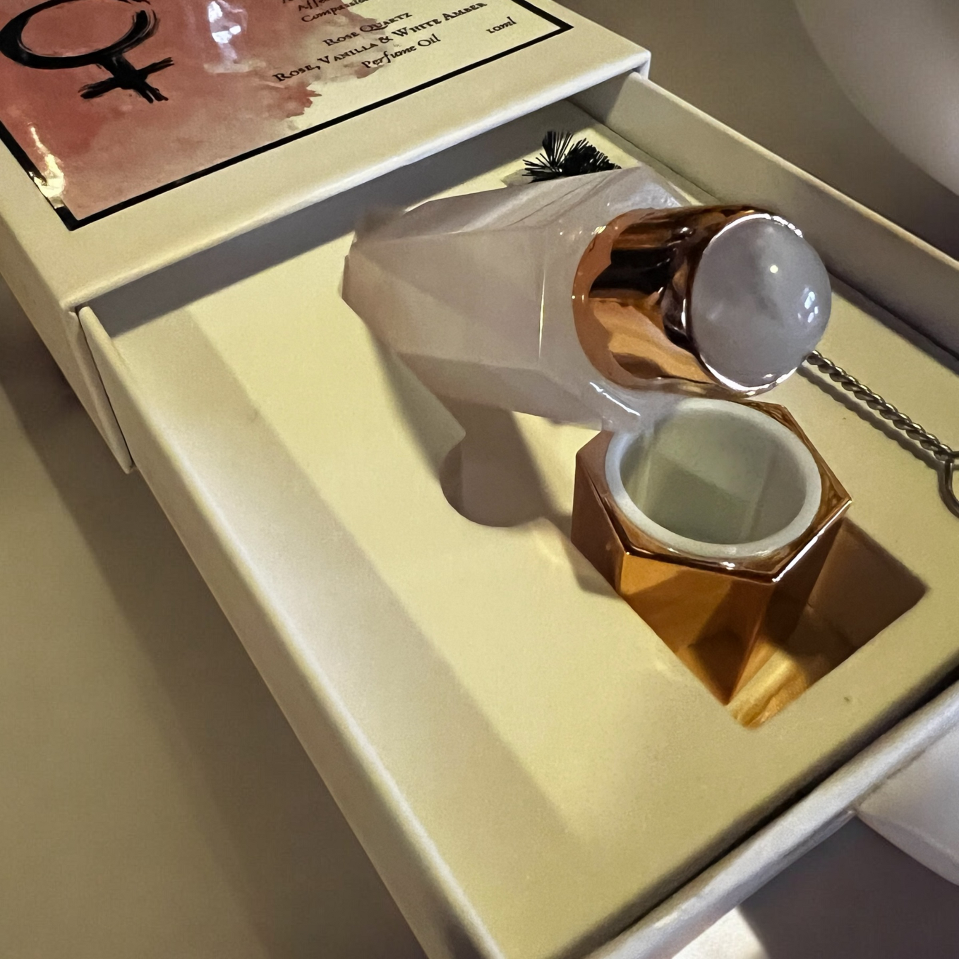 Detailed view of a product box containing a Rose Quartz perfume bottle and accessories, emphasizing the luxurious design and presentation.